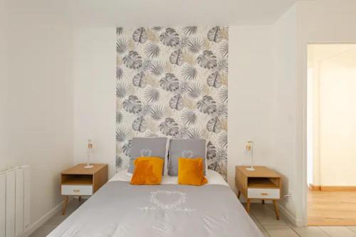 een slaapkamer met een wit bed en 2 oranje kussens bij L'escale des vignobles in Gevrey-Chambertin