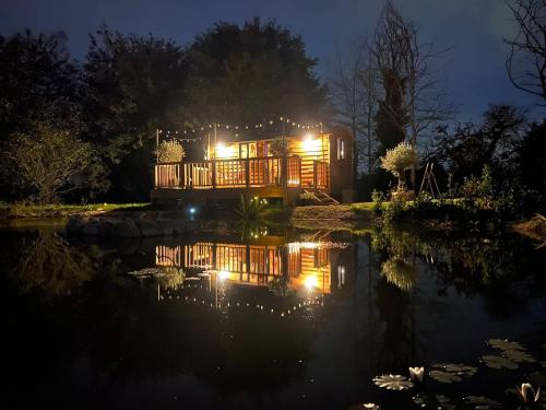謝菲爾德的住宿－Rusty Duck Retreat Shepherds Hut，池塘旁的房屋晚上被点燃