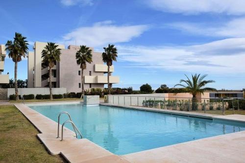 uma grande piscina com palmeiras em frente a um edifício em Apartamento Golf Lujo Mor 2, Valle del Este Vera em Vera