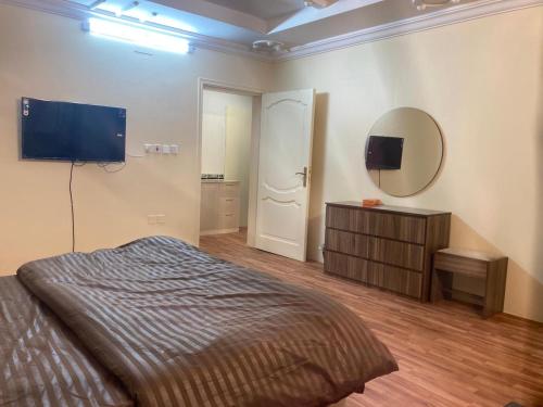 Al-mohamdiah apartments في مكة المكرمة: غرفة نوم بسرير وتلفزيون بشاشة مسطحة