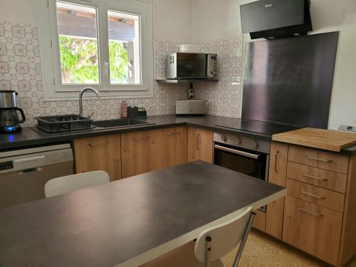 una cucina con mobili in legno e un piano di lavoro di Villa catalane avec grand jardin, au calme, mer et montagne a Sorède