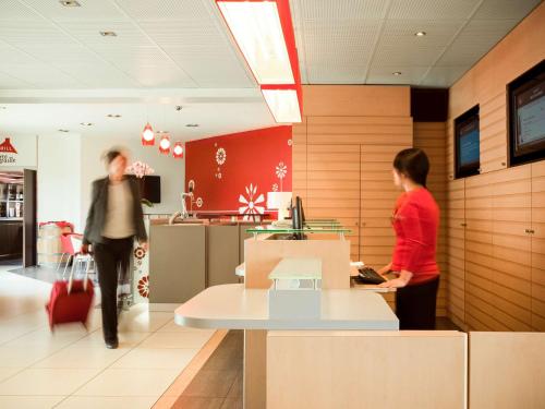 a man and a woman standing in a lobby at ibis Senlis in Senlis