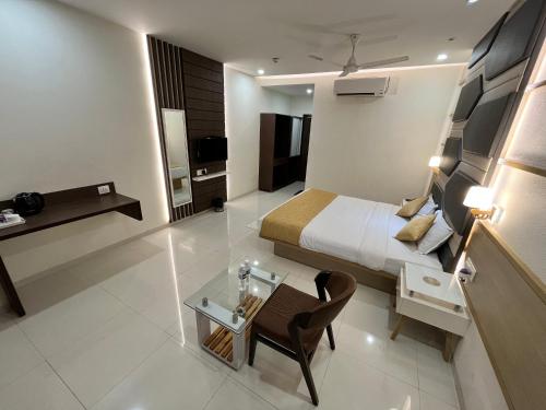 a hotel room with a bed and a glass table at Hotel Grand Darshan Vadodara in Vadodara