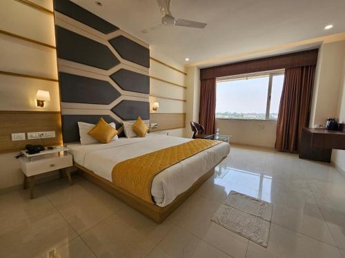 a bedroom with a large bed and a large window at Hotel Grand Darshan Vadodara in Vadodara