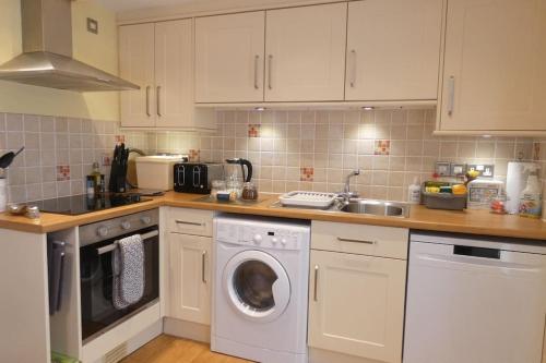 a kitchen with a washing machine and a sink at Two Bedroomed Holiday Cottage with Sea Views in St Austell