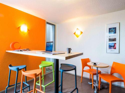 a bar with colorful stools and a laptop on a counter at ibis budget Châtellerault Nord in Châtellerault