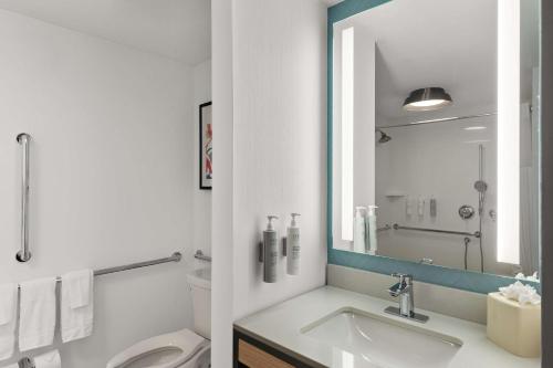 a bathroom with a sink and a toilet and a mirror at Hilton Garden Inn Atlanta East/Stonecrest in Lithonia