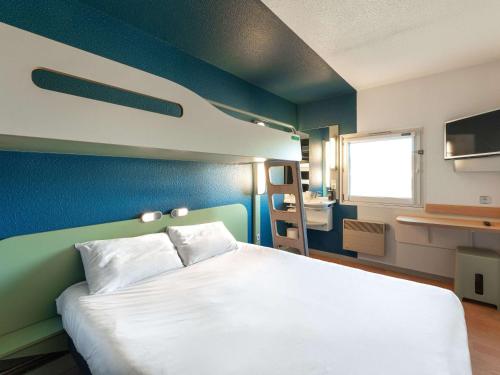 1 dormitorio con cama blanca y pared azul en ibis budget Mâcon Nord, en Mâcon