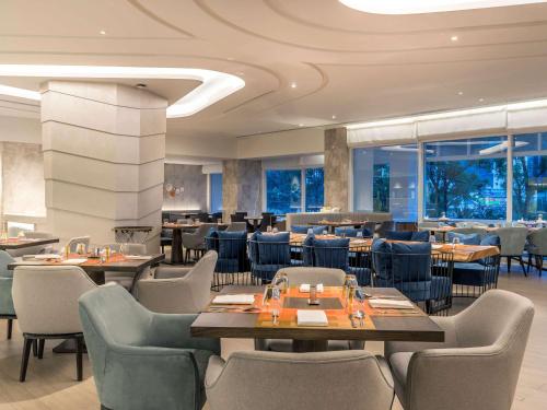 a dining room with tables and chairs and a restaurant at Novotel Phuket City Phokeethra in Phuket