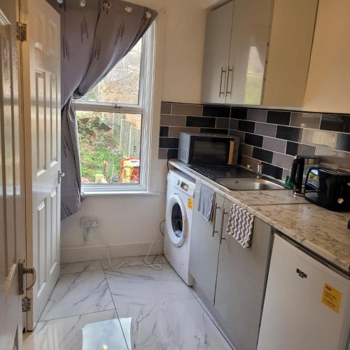 a kitchen with a washing machine and a window at Greenwich City Staycation in Plumstead