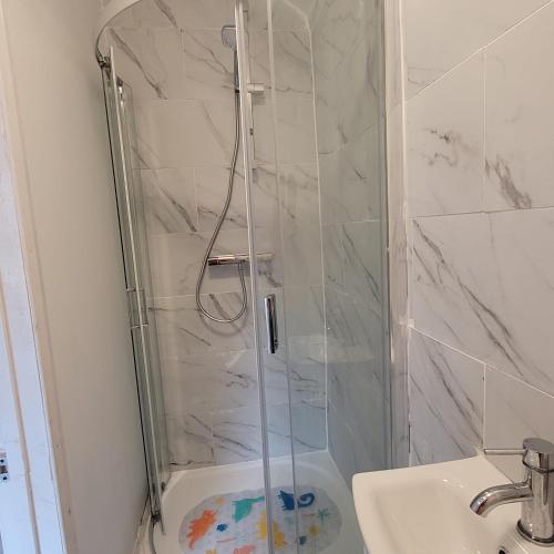 a shower with a glass door in a bathroom at Greenwich City Staycation in Plumstead