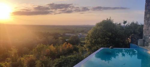 a swimming pool with the sunset in the background at Le Prieuré de Saint Pierre in Saint-Pey-de-Castets