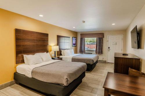 ロックポートにあるQuality Inn Rockport on Aransas Bayのベッド2台とデスクが備わるホテルルームです。