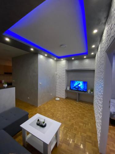 a living room with a white table and a tv at Play Apartman Obrenovac in Obrenovac