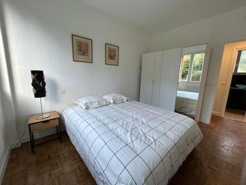Un dormitorio con una cama y una mesa con una lámpara. en Appart - proche gare - 4 pers, en Vaucresson