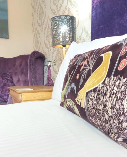 a bed with a pillow and a table with a lamp at Invergarry Room Only Guest House For Adults in Windermere