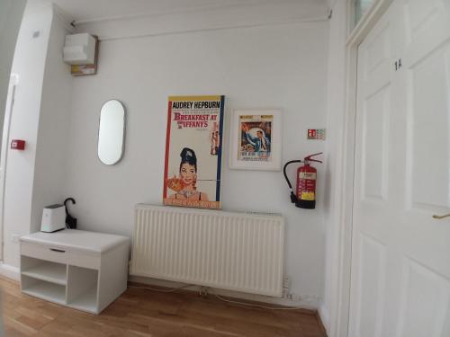 Habitación blanca con radiador y posters en la pared en Kensington Secret Gem, en Londres