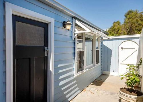 niebieski dom z czarnymi drzwiami i werandą w obiekcie Studio 39 w mieście Shepparton