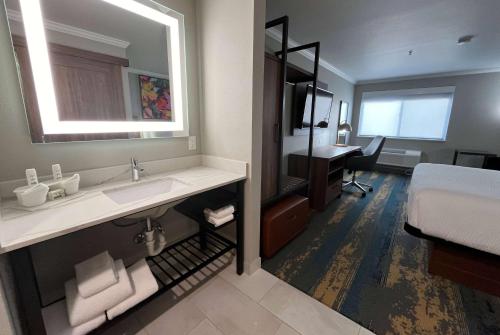 a bathroom with a sink and a bed and a desk at La Quinta Inn & Suites by Wyndham Yakima Downtown in Yakima