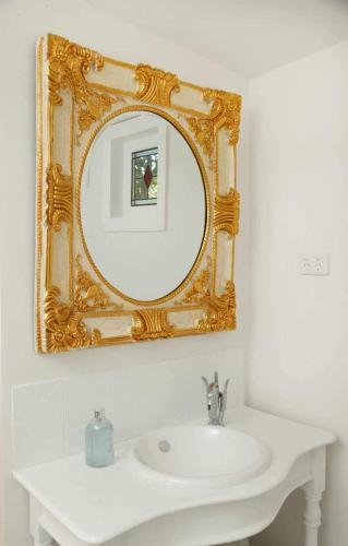 a bathroom with a white sink and a gold mirror at Studio 39 in Shepparton