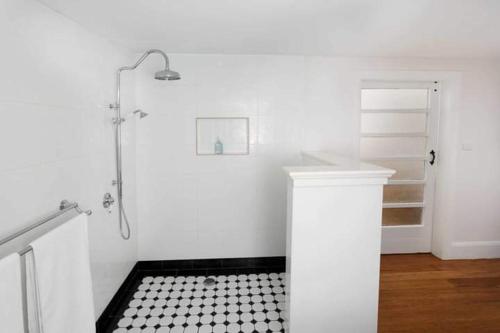 a white bathroom with a shower and a black and white tiled floor at Studio 39 in Shepparton