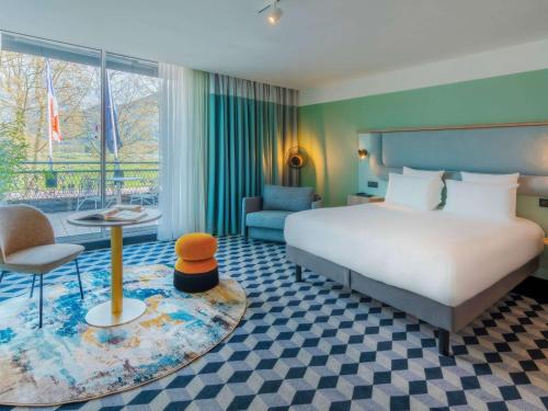 Le Splendid Hotel Lac D'Annecy - Handwritten Collection في أنِسي: غرفه فندقيه بسرير وكرسي وطاولة