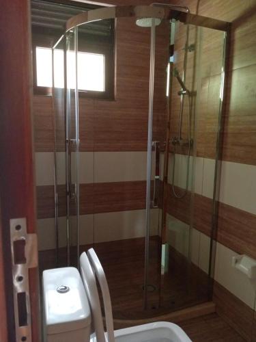 a bathroom with a toilet and a glass shower at KIM UNIVERSITY TWO ROOMS APARTMENT in Kigali