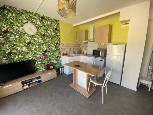 uma cozinha com uma mesa, um frigorífico e uma televisão em AS24540- P2 neuf à 100m de la Plage em Le Grau-du-Roi