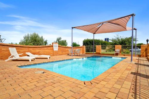 a swimming pool with an umbrella and chairs at Comfort Inn Bishops Lodge in Hay