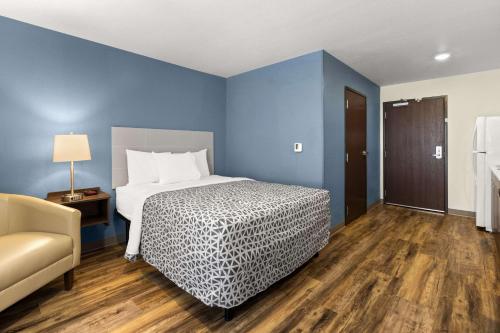 a bedroom with a bed with blue walls and a chair at WoodSpring Suites Bowling Green I-65 in Bowling Green