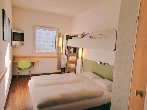 Habitación con 2 camas, escritorio y litera. en ibis budget Berlin Ost en Berlín