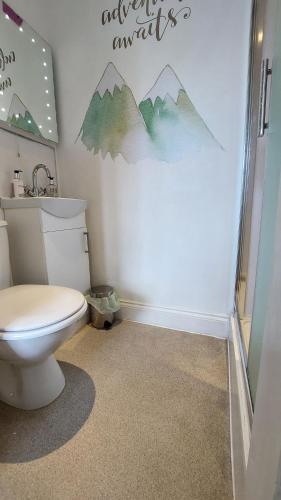 a bathroom with a toilet and mountains on the wall at Invergarry Room Only Guest House For Adults in Windermere