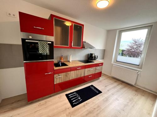 a kitchen with red cabinets and a large window at Soleblick 