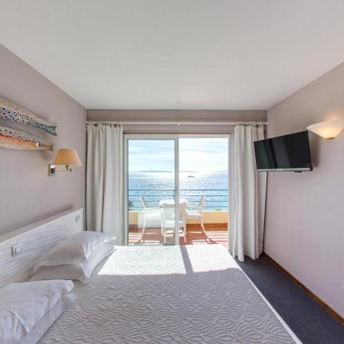 une chambre avec un lit et une vue sur l'océan dans l'établissement Grand Hotel Moriaz, au Lavandou