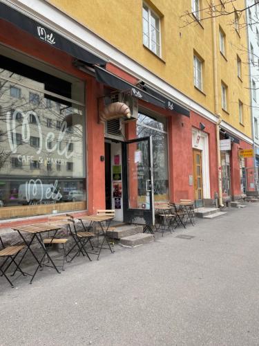 Your Chic Vibrant Airbnb في هلسنكي: واجهة متجر مع طاولات وكراسي في شارع