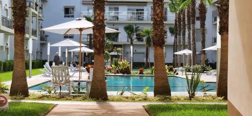 a resort with a pool and palm trees and a building at Shems Bouznika kettani in Bouznika