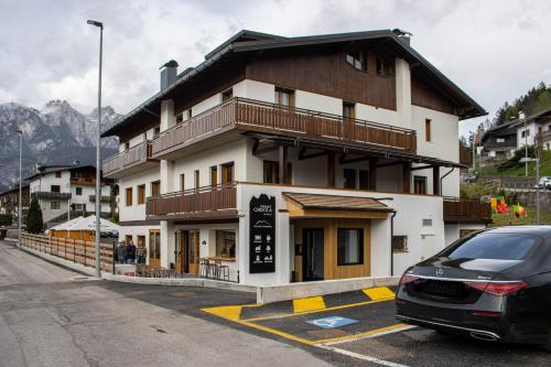 Chalet Cridola Dolomiti Experience في Lorenzago: مبنى متوقف امامه سيارة