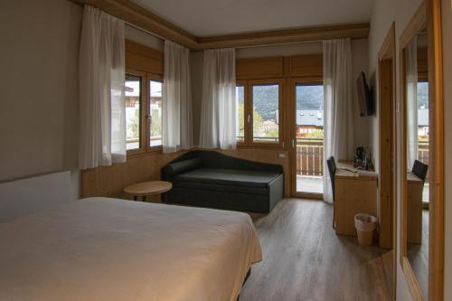 a hotel room with a bed and a couch at Chalet Cridola Dolomiti Experience in Lorenzago