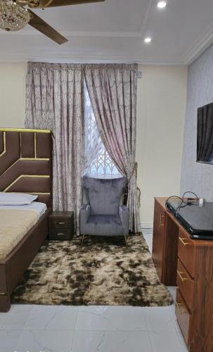 a bedroom with a bed and a chair and a window at Sugarville, Swimming pool with a Rooftop in Accra