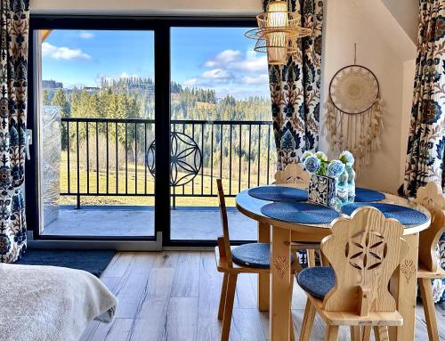 een kamer met een tafel en stoelen en een balkon bij Domek Tatry - Stacja Wierchowa 972 m in Brzegi
