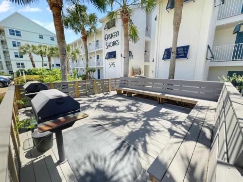a picnic bench in front of a building with palm trees at Endless Waves -208 ES Condo in Santa Rosa Beach
