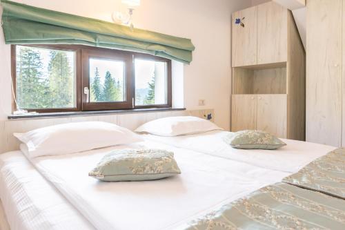 two white beds in a room with a window at Pensiunea Hilltop in Predeal