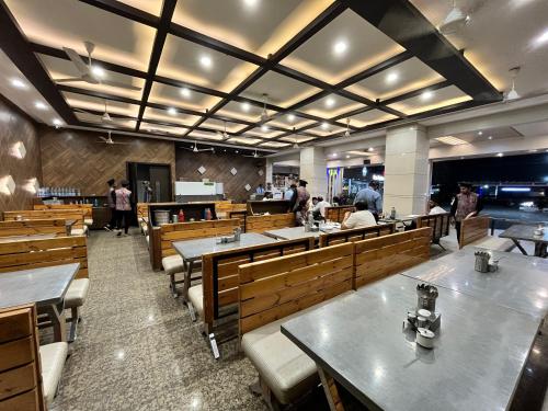 a dining room with tables and benches and people in it at Hotel Grand Darshan Vadodara in Vadodara