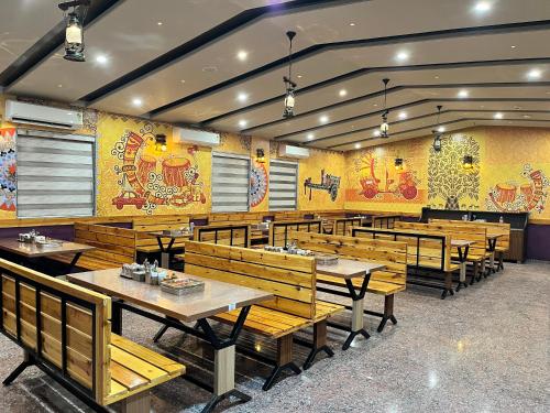 a dining room with wooden tables and benches at Hotel Grand Darshan Vadodara in Vadodara