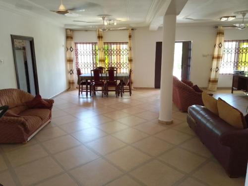 a living room with couches and a table and chairs at Kim's Guest House in Kasoa