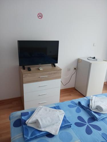Guest House Vasilevi في نيسيبار: غرفة نوم مع تلفزيون وسرير مع مناشف