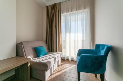 a room with a couch and a chair and a window at Hotel Sato Conference & SPA Resort in Sutomore