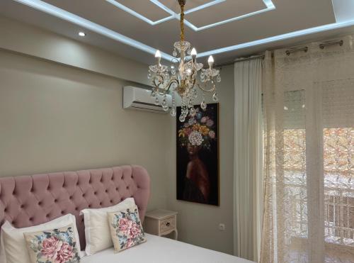 a bedroom with a pink bed and a chandelier at AGORA luxury APARTMENT 10 in Loutraki