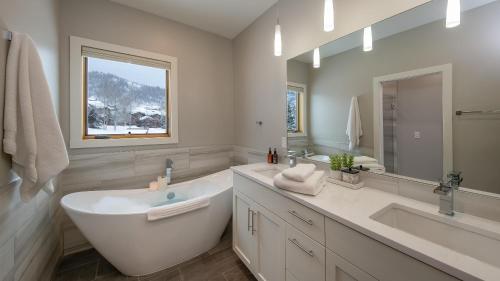 Baño blanco con bañera y lavamanos en Chalet Memoire en Steamboat Springs