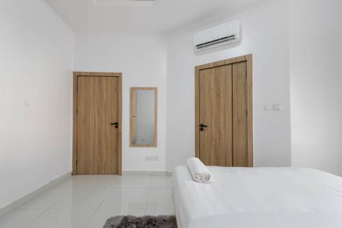 a white room with a bed and two wooden doors at Firenze Apartments Lekki in Lagos